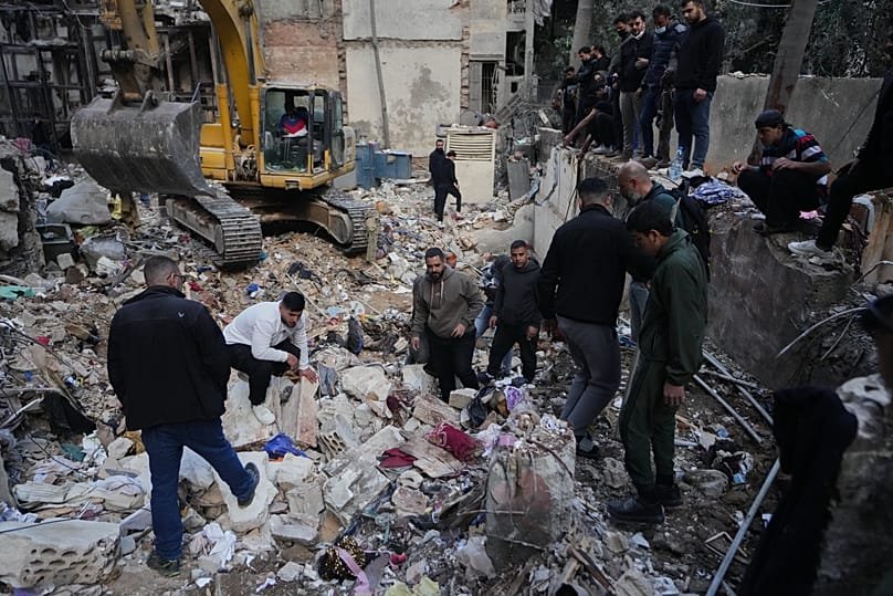 Civilians and rescue workers search through rubble at the site of a building destroyed in an Israeli strike in central Beirut, 12 April, 2026