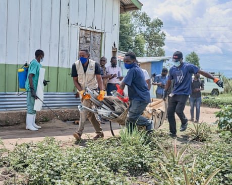 Aid workers in face masks carry a stretcher with equipment and supplies outside a building