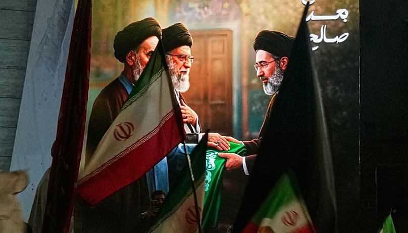 Protesters wave Iranian flags and hold a portrait of the late Iran's Supreme Leader Ayatollah Ali Khamenei and his son Ayatollah Mojtaba Khamenei to support his selection as t