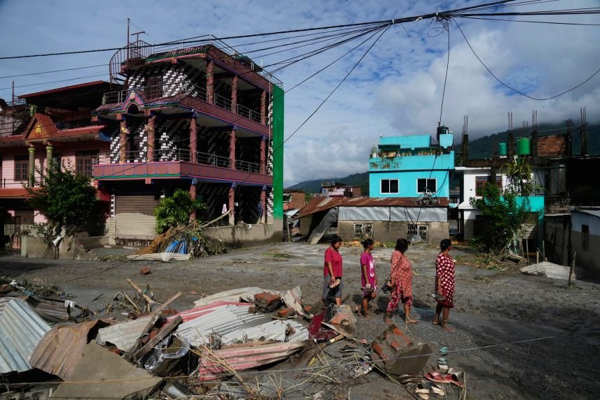 People walk past damage in the aftermath of flash floods in Devighat in the Nuwakot district in Nepal, on August 27.