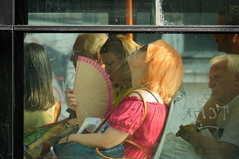 FILE - A woman uses a fan to cool off while riding a bus on a hot day in Bucharest, Romania, Aug. 6, 2026. 
