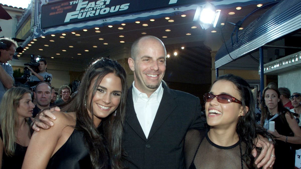 Neal Moritz, Jordana Brewster, and Michelle Rodriguez stand together at a film premiere.